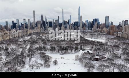 Eine kinematografische Großaufnahme der Skyline von New York City und der Gapstow Bridge im Central Park, die tagsüber mit frischem Winter Schnee bedeckt ist. Stockfoto