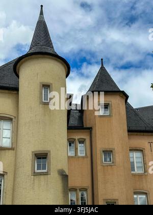 Historische Burgtürme mit schindelartigen Kegeldächern und Fenstern. Historische europäische Burgtürme mit gelben verputzten Wänden, schindelartigen Kegeldächern, ein Stockfoto