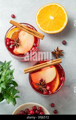 Ein Cranberry-Getränk in zwei Gläsern auf einem hellen Hintergrund mit Zimt, Beeren und Zitrusfrüchten. Ein traditioneller Weihnachtspunsch oder Glühwein mit oder Stockfoto