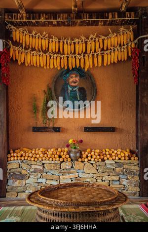 Rustikale Inneneinrichtung mit getrocknetem Mais und einem Porträtgemälde eines Hmong-Ältesten, Y Ty, Lao Cai, Vietnam Stockfoto