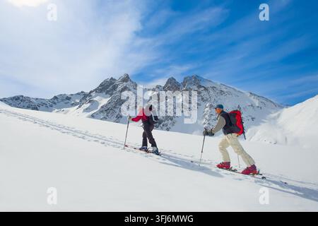 Zwei ältere Alpinskifahrer Klettern auf Skiern und Fellen Stockfoto