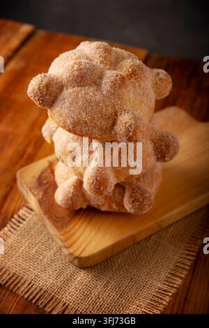 Pan de Muerto. Traditionelles mexikanisches Süßbrot, mit Zucker überzogen, auf einem Holzschneidebrett, perfekt für den Tag der Toten. Stockfoto