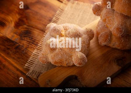 Pan de Muerto. Traditionelles mexikanisches Süßbrot, mit Zucker überzogen, auf einem Holzschneidebrett, perfekt für den Tag der Toten. Stockfoto