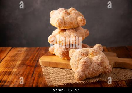 Pan de Muerto. Traditionelles mexikanisches Süßbrot, mit Zucker überzogen, auf einem Holzschneidebrett, perfekt für den Tag der Toten. Stockfoto