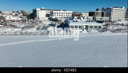 Ozeanstrand, der im Winter mit Schnee bedeckt ist. Luftbild eines Lastwagens von den Hotel- und Motelgebäuden in Cape May, New Jersey. Für die Saison geschlossen. Stockfoto