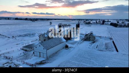 Ländlicher Familienbauernhof im Winter Schnee bei Sonnenuntergang. Orbit zeigt Amische Scheune und Bauernhaus, frischer Schneesturm, Lampeter, Pennsylvania. Stockfoto