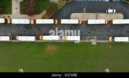 Top-Down-Luftaufnahme einer Reihe von Schulbussen. Schüler steigen aus und gehen zu den Schulbussen. Truck-Aufnahme, Lovingston, Virginia. Stockfoto