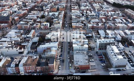 Luftaufnahme über ein Viertel in Baltimore, die dichte Reihen klassischer Stadthäuser, gerade Straßen, geparkte Autos und das städtische Raster eines amerikanischen Ostens offenbart Stockfoto