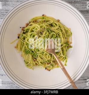 Spaghetti mit grüner Pesto-Sauce aus wildem Knoblauch, Olivenöl und Pinienkernen auf einer Gabel im Teller, Nahaufnahme, Ansicht von oben Stockfoto