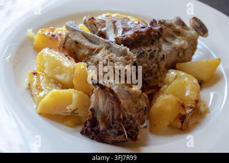 Nahaufnahme von gebratenem Lammkarré mit goldenen Röstkartoffeln, ein traditionelles italienisches Ofengeschirr mit Fleisch auf einem weißen Teller Stockfoto