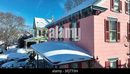 Viktorianische Häuser in Rosa und Grün gestrichen mit Winter Schnee und Eiszapfen vom Dach. Amerikanische Flagge in der Weihnachtszeit, Cape May, New Jersey. Stockfoto