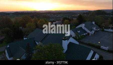 Steigende Enthüllung des Tals mit entfernten Häusern und Geschäftsgebäuden. Dramatischer Sonnenaufgang am Horizont, weißer Raum. Luftaufnahme, Morgantown, West Virginia. Stockfoto