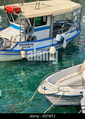 Kreta, Griechenland – 28. August 2026: Traditionelles kleines Fischerboot, das neben einem Yachthafen in kristallklarem türkisfarbenem Wasser liegt, mit blauen und weißen Details Stockfoto