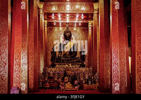 Sitzende Buddha-Statue in einem kunstvoll verzierten buddhistischen Tempel im Zentrum von Vientiane, Laos Stockfoto