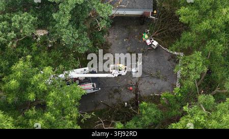 Baggerwagen-Linienmann repariert einen gebrochenen Strommast, der in Drähten auf der Einfahrt in Manheim Township, Pennsylvania, verheddert ist, dichter Baumkronen umgeben den Sturm Stockfoto