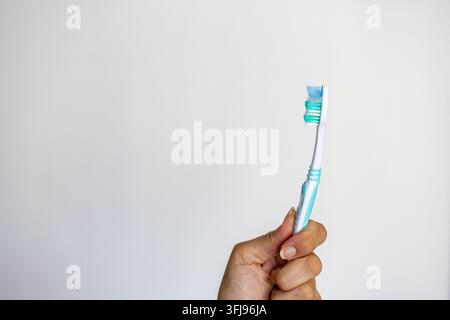 Eine Nahaufnahme einer weißen und grünen Plastikzahnbürste mit blauen und grünen Borsten vor einem schlichten weißen Hintergrund mit Kopierraum Stockfoto
