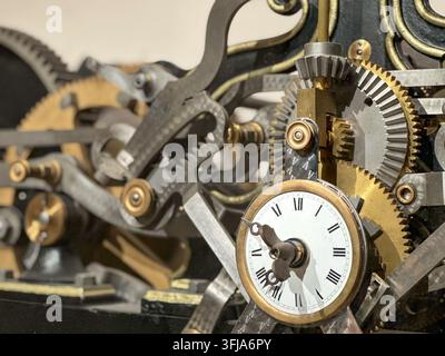 Detaillierte Nahaufnahme von kunstvollen mechanischen Uhrrädern und römischen Ziffernblatt. Kunstvolle Nahaufnahme von komplexen mechanischen Uhrrädern, Zahnrädern und Met Stockfoto