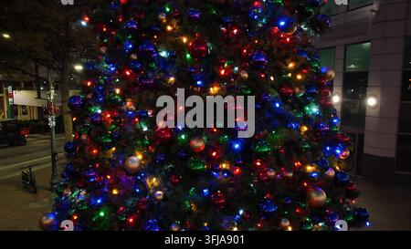 Weihnachtsbaum im Freien in der Innenstadt einer amerikanischen Stadt bei Nacht. Lichter funkeln und glänzende Ornamente. Steigender Luftorbit, Memphis, Tennessee. Stockfoto