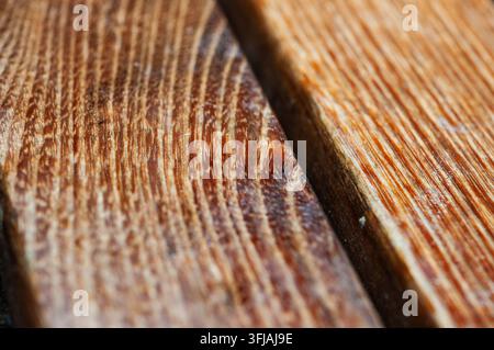 Nahaufnahme von zwei braunen Holzplanken. Auf der Holzoberfläche sind deutliche natürliche Maserungen sichtbar. Eine dunkle Linie trennt die beiden Stücke. Stockfoto