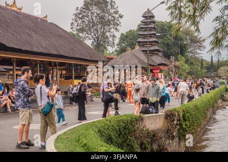 Massen von Touristen besuchen den ikonischen Pura Ulun Danu Beratan Tempel am Rand des Sees, machen Fotos und gehen spazieren. Stockfoto