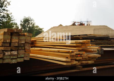Gestapelte Holzplanken und Bauholz auf einer Baustelle im Freien, die rohe Baumaterialien für Infrastruktur- und Tischlerprojekte zeigen Stockfoto