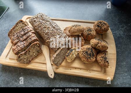Handwerkliches Brot und gesäte Brötchen auf einem Holzbrett arrangiert Stockfoto