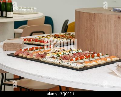 Verschiedene herzhafte Canapés und Fingerfoods, die auf Serviertabletts bei einer Empfangsparty präsentiert werden Stockfoto