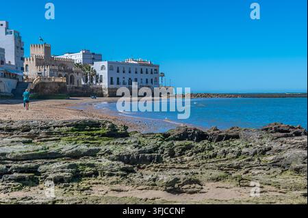 CHIPIONA, SPANIEN - 5. APRIL 2023: Blick auf die Küstenstadt Chipiona in der Provinz Cadiz, Andalusien, Spanien, mit Menschen am Sandstrand und dem Meer Stockfoto