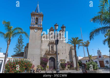 CHIPIONA, SPANIEN - 5. APRIL 2023: Blick auf die Plaza Juan Carlos I in Chipiona, Provinz Cadiz, Andalusien, Südspanien, mit der Fassade und dem Glockenturm von Stockfoto