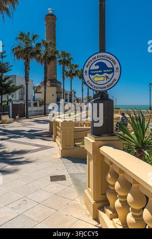 CHIPIONA, SPANIEN - 5. APRIL 2023: Blick auf ein Tsunami-Warnschild, das einen Evakuierungsweg an der Uferpromenade in Chipiona, Provinz Cádiz, Andalusien zeigt Stockfoto