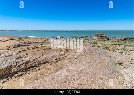 Blick auf den Strand in Chipiona, Provinz Cadiz, Andalusien, Spanien, mit Felsen im Vordergrund, Sand, Meer und Himmel entlang der Atlantikküste Stockfoto