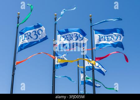San Francisco, CA, USA - 4. Juni 2026: Windgepeitschte Fahnen entlang des Pier 39-Wasserrands. Stockfoto