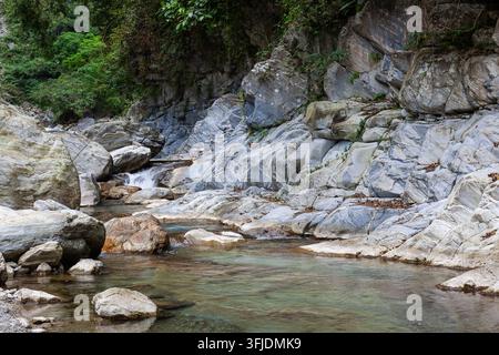 Sanzhanxi-Fluss in Taroko, Hualien, Taiwan. Klares Wasser fließt über große graue Felsen. Üppiger grüner Wald an den Berghängen. Stockfoto
