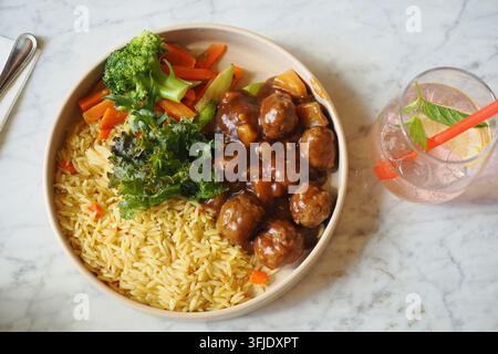 Essteller mit Reis, Gemüse und Frikadellen auf Marmortisch Stockfoto