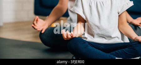 Eine Mutter und ihre Tochter genießen Familien-Yoga und finden Glück und Zusammenhalt, während sie im Lotussitz sitzen und sich auf Achtsamkeit und Meditation konzentrieren. Stockfoto