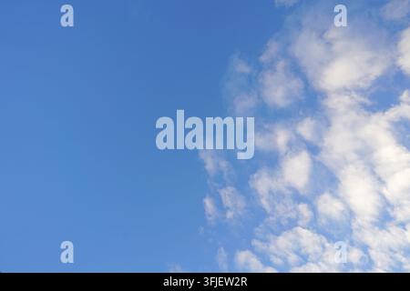 Klarer blauer Himmel mit weichen weißen Wolken in der Ecke, der einen sauberen natürlichen Hintergrund und Vorlagen schafft. Stockfoto