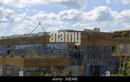 Verlassenes Industriegebäude, das ein Bild städtischen Verfalls und Vernachlässigung zeigt mit zerbrochenen Fenstern, überwucherter Vegetation und einer verwitterten Fassade Stockfoto