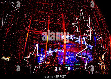 Nahaufnahme von hellroten und blauen Weihnachts-LED-Lichtern und leuchtenden Stern-Dekorationen, die eine festliche Weihnachtsausstellung in der Nacht beleuchten. Stockfoto