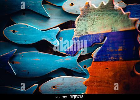 Nahaufnahme von handgefertigten Holzhandwerken mit blau bemaltem Fisch und einer bunten Seepferdchen-Dekoration in einer traditionellen Werkstatt. Stockfoto