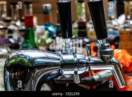 Ein polierter Chrom-Doppelbierhahn mit schwarzen Zapfhähnen auf einer Theke. Stockfoto