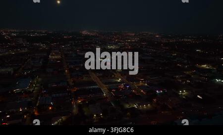 Luftflug über eine amerikanische Stadt bei Nacht. Vollmond am dunklen Himmel. Thema Bevölkerung in den USA, Houston, Texas. Stockfoto