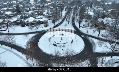 Luftaufnahme eines großen Kreisverkehrs im Winter. Schnee auf dem Boden und Autos fahren in einer amerikanischen Wohnsiedlung, Wyomissing, Pennsylvania. Stockfoto