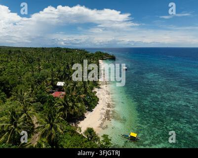 Tropische Küste mit Palmen, sandigem Strand und Fischerbooten entlang der türkisfarbenen See. Camotes, Philippinen. Stockfoto