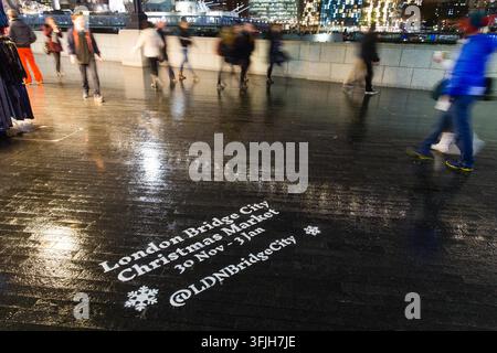 Menschen schlendern den Thames Path entlang der HMS Belfast, angezogen vom London Bridge City Weihnachtsmarkt für festliche Weihnachtsstimmung. Stockfoto