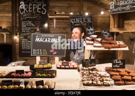 Ein Verkäufer verkauft fröhlich festliche Macarons und Brownies an Feiertagseinkäufer am More London Riverside, nahe der Tower Bridge. Stockfoto