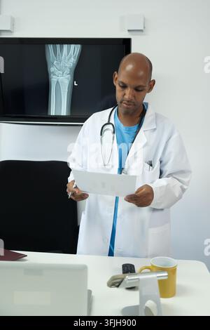 Arzt untersucht medizinische Unterlagen und radiologische Bilder in einer modernen Klinik Stockfoto