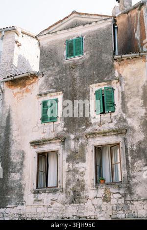 Verwittertes Steingebäude mit grünen Fensterläden Stockfoto