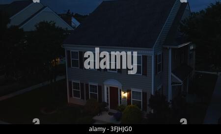 Mehrfamilienhaus bei Nacht. Aufsteigende Luftaufnahme während der Blauen Stunde der Dämmerung eines Hauses mit eingeschaltetem Außenlicht, Roseville, Pennsylvania. Stockfoto