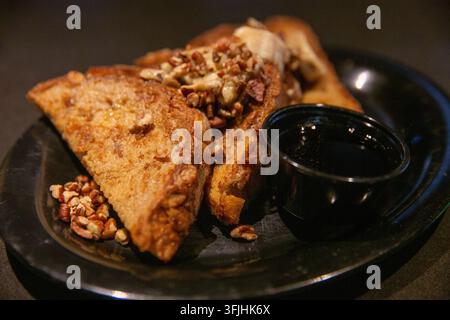 Eine Nahaufnahme, horizontal aufgenommen, zeigt ein herzhaftes Frühstücksgericht mit goldbraunen French-Toast-Dreiecken, die mit Bananenscheiben und Crus garniert sind Stockfoto