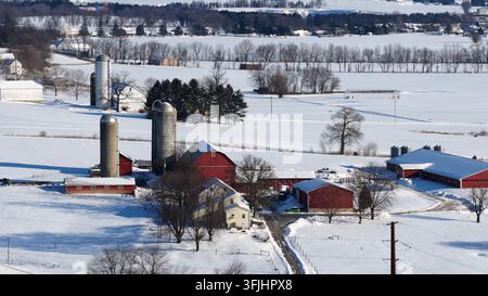 Luftbild von rotem Stall und Silos auf verschneitem Farmland in Pennsylvania mit Bauernhaus und ländlichen Feldern im Winter. Weitwinkelaufnahme. Ruhiger und friedlicher Vorort d Stockfoto